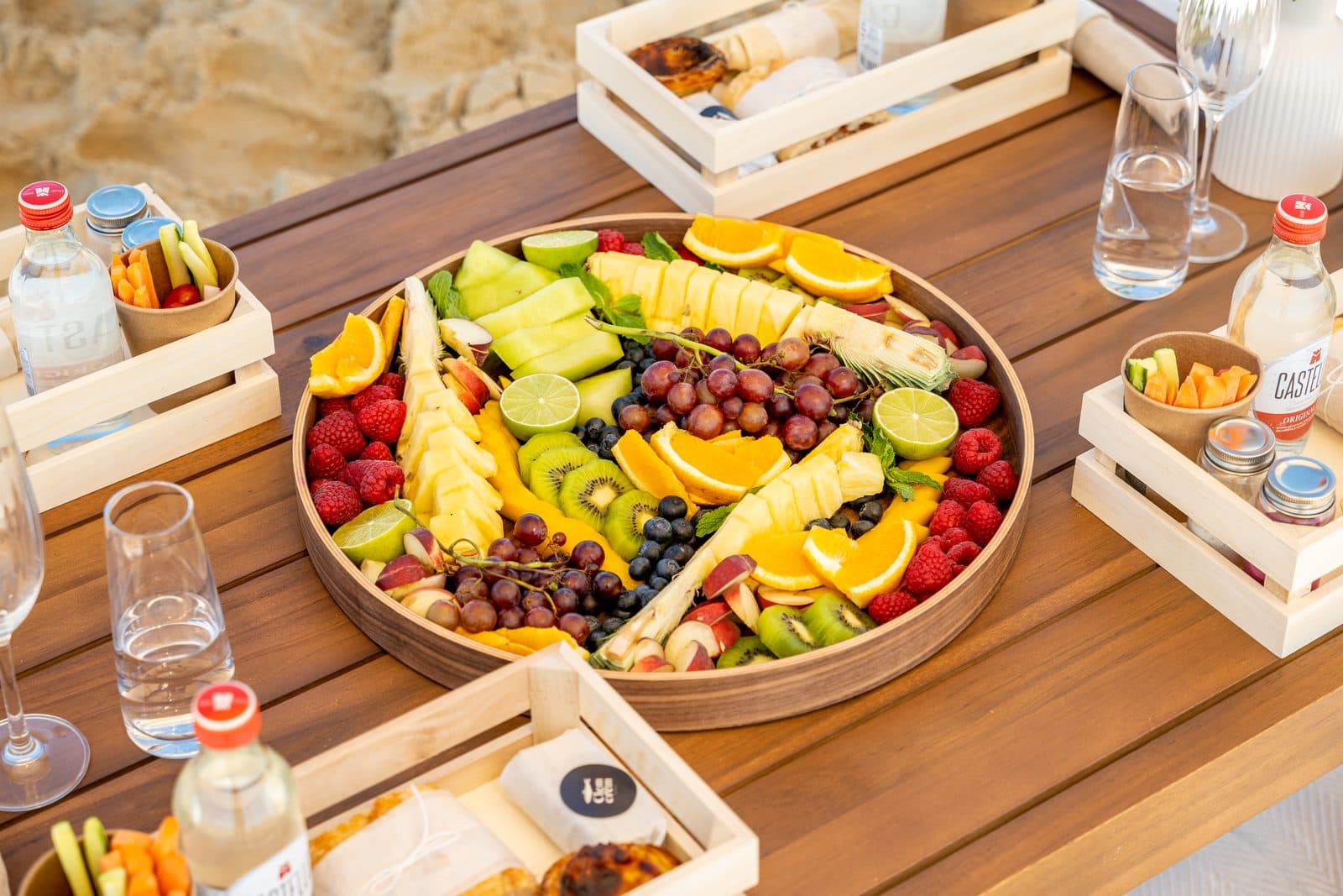 A fruit platter and individual wooden picnic boxes on a low table